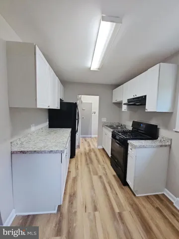 a large kitchen with granite countertop a sink a stove top oven a counter space and cabinets