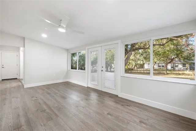 an empty room with wooden floor and windows