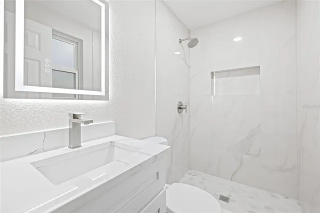 a bathroom with a granite countertop sink a toilet and shower