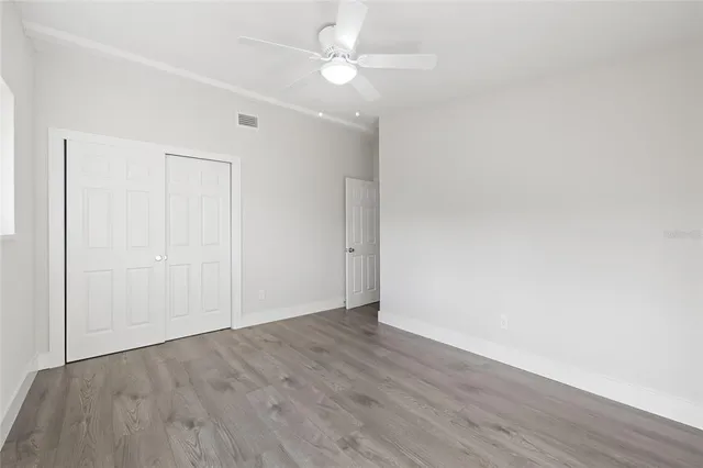 an empty room with wooden floor and fan