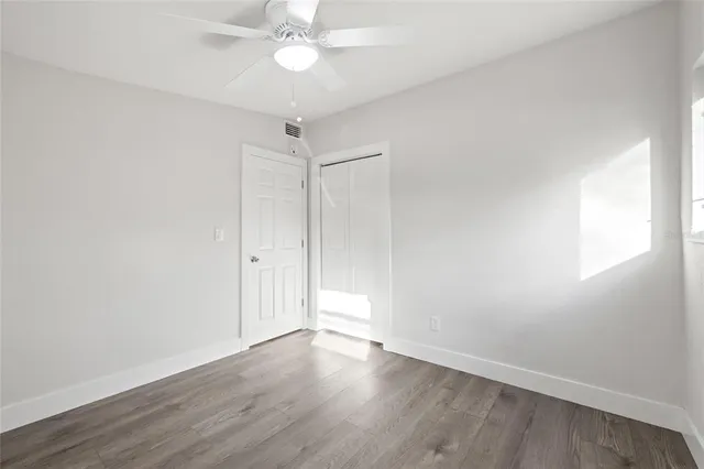 an empty room with wooden floor and fan