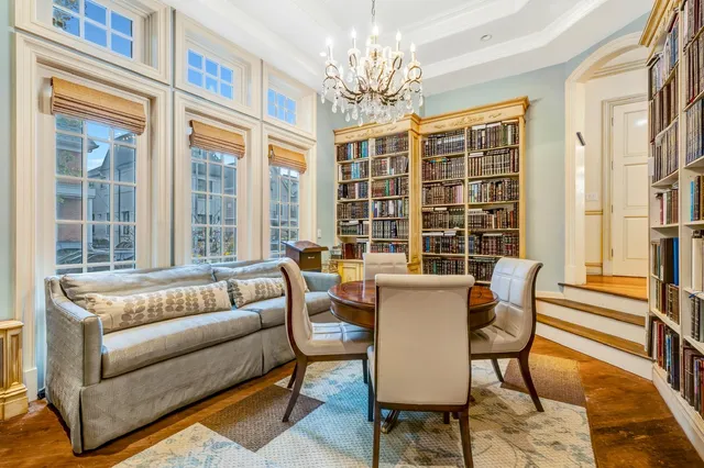 a view of a dining room with furniture a chandelier and large window