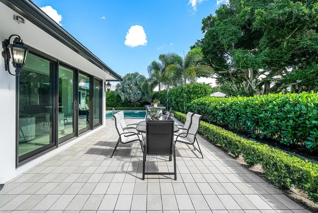 a view of a patio with table and chairs potted plants and floor to ceiling window