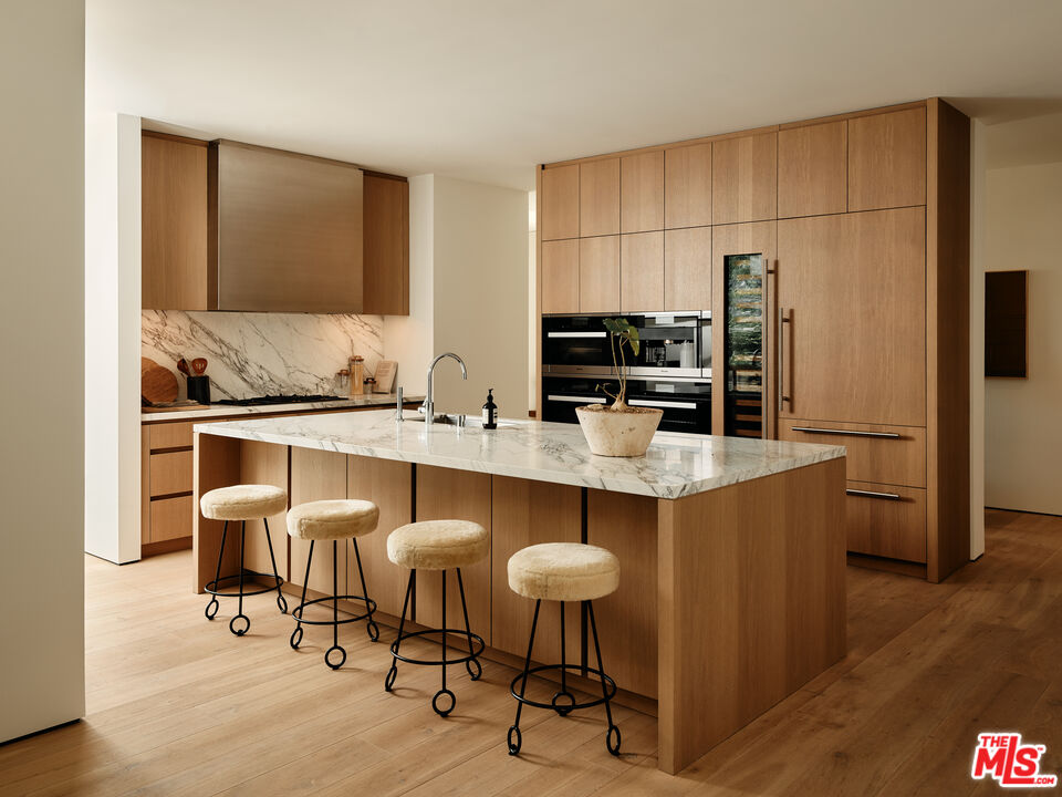 8899 Beverly Boulevard, Unit 4D Los Angeles, CA 90048 - Photo 4 of 28 a kitchen with stainless steel appliances a sink a table and chairs in it