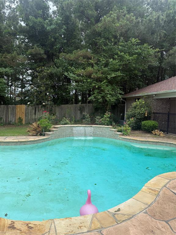 201 Woodhaven Drive Minden, LA 71055 - Photo 29 of 31 Freeform swimming pool with stone coping, a tiered waterfall feature, and surrounding mature trees