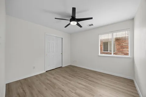 a view of empty room with wooden floor and fan