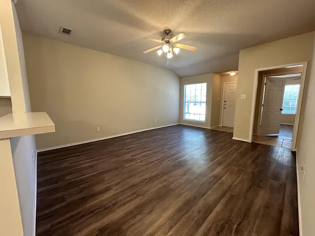 a view of an empty room with wooden floor and a window