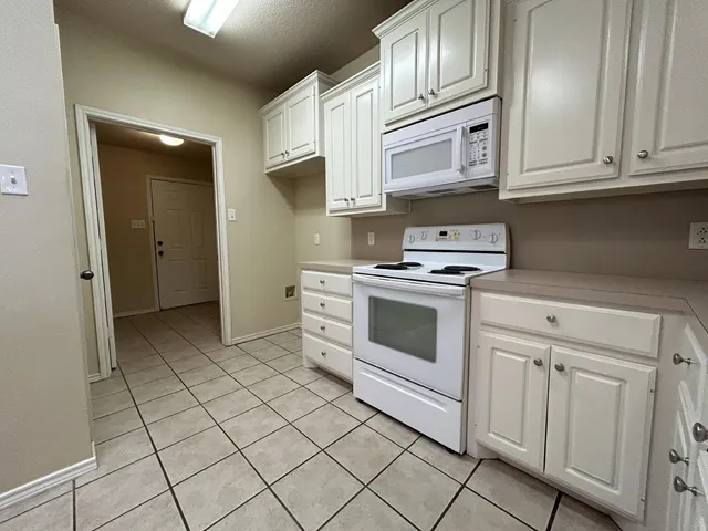 a kitchen with stainless steel appliances granite countertop white cabinets and stove top oven