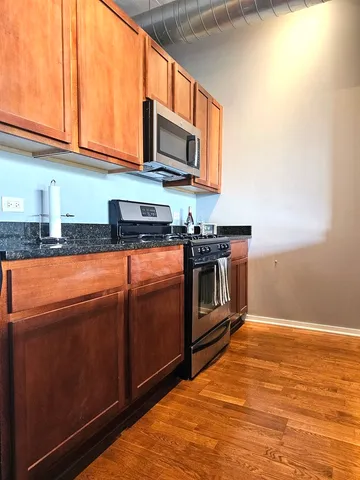 a kitchen with stainless steel appliances granite countertop a stove a sink and a microwave