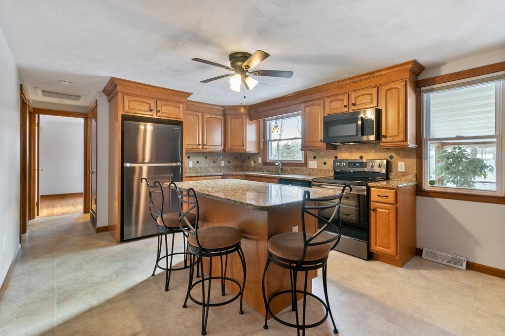 35 Helberg Road Springfield, MA 01128 - Photo 3 of 25 a kitchen with stainless steel appliances granite countertop a refrigerator a stove a microwave oven with a dining table and chairs with wooden floor