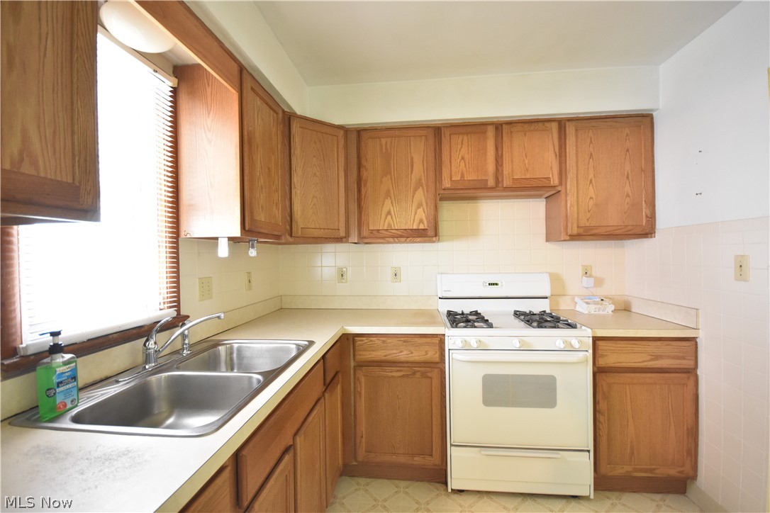 31921 Pendley Road Willowick, OH 44095 - Photo 5 of 22 Kitchen featuring sink, white gas range oven, backsplash, and light tile flooring
