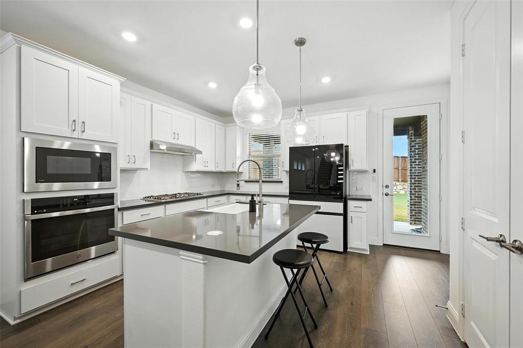 447 Holly Road Little Elm, TX 75068 - Photo 14 of 30 a kitchen with stainless steel appliances granite countertop a sink refrigerator and microwave