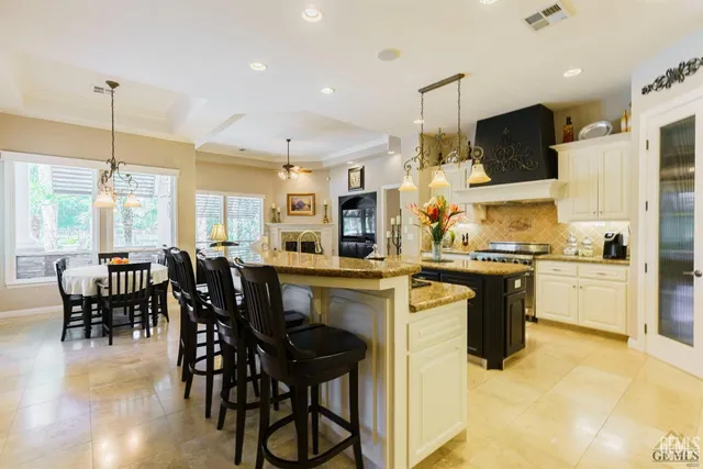 a kitchen with stainless steel appliances kitchen island granite countertop a table chairs sink and cabinets