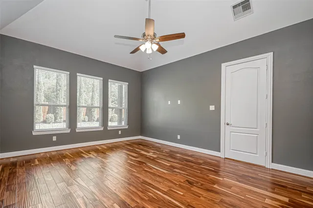 a view of an empty room with window and wooden floor