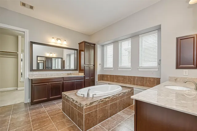 a spacious bathroom with a granite countertop tub sink and mirror