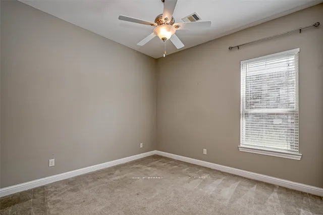 an empty room with a window and a fan