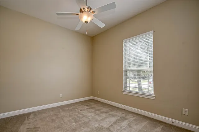 an empty room with a window and a fan