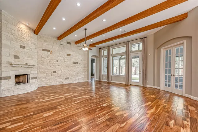 a view of an empty room with wooden floor and a fireplace