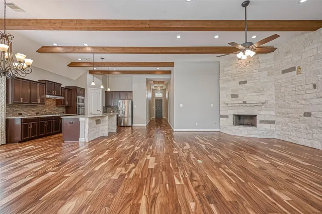 a view of kitchen and empty room with wooden floor