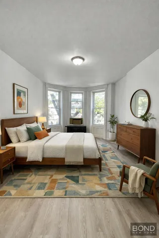 a spacious bedroom with a bed a couch and large window