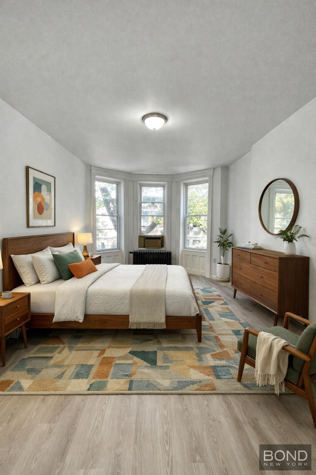 60-36 68th Road, Unit 2 Queens, NY 11385 - Photo 2 of 5 a spacious bedroom with a bed a couch and large window