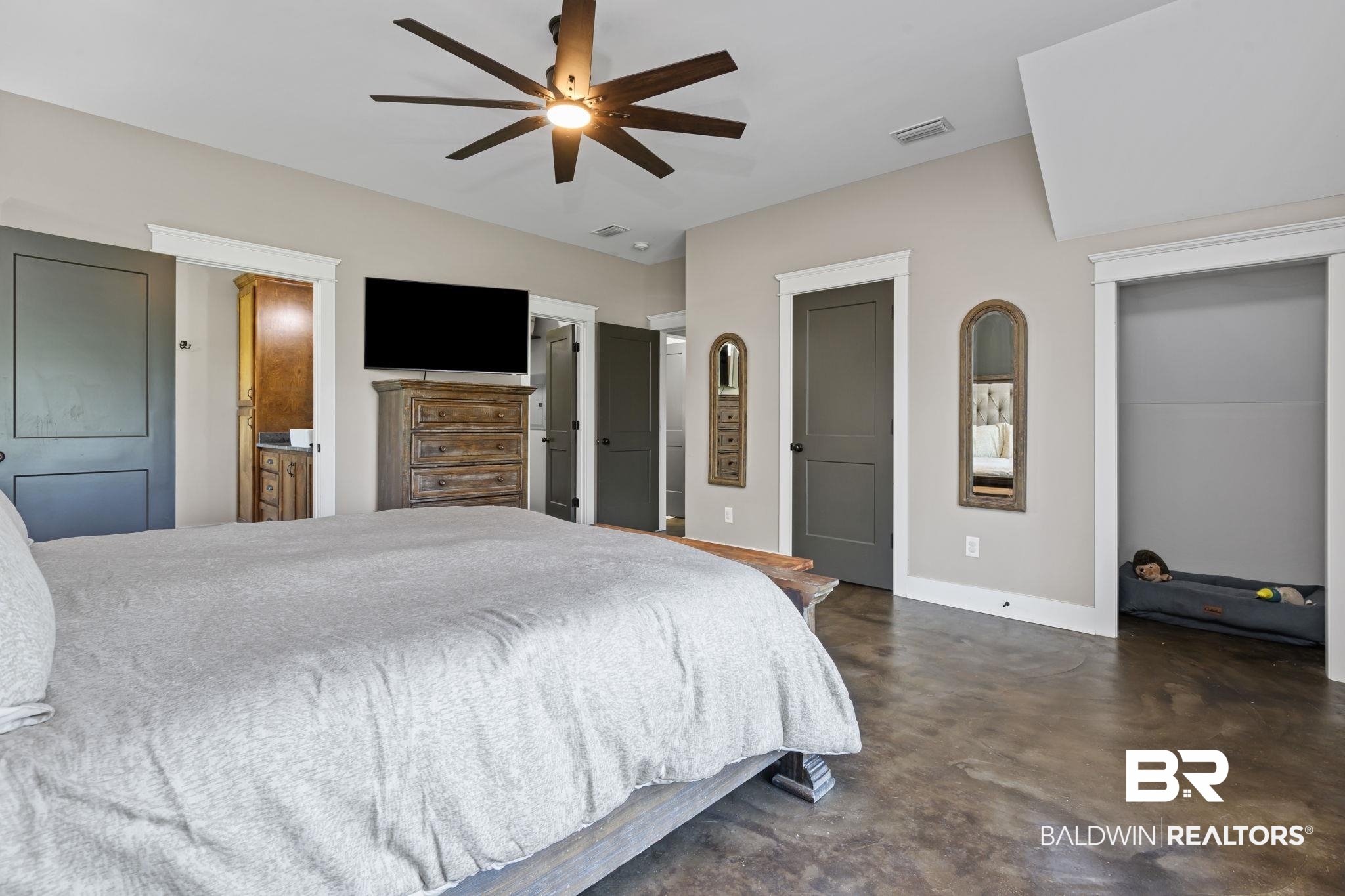 11025 Creax Road Axis, AL 36505 - Photo 22 of 45 Spacious bedroom featuring dark concrete-finish flooring, a contemporary ceiling fan, and multiple dark paneled doors