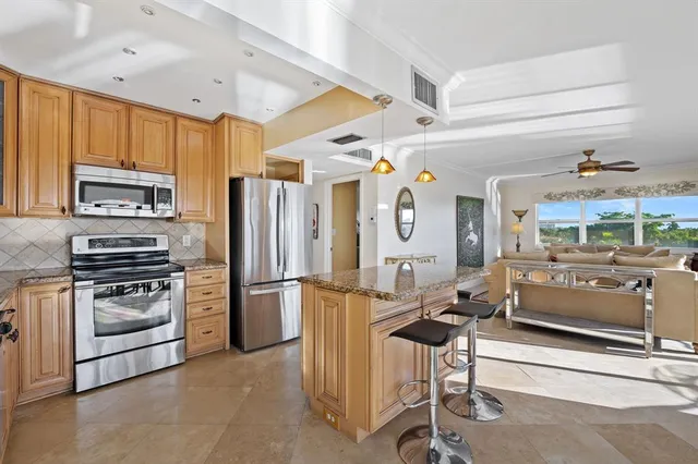 a kitchen with stainless steel appliances kitchen island granite countertop a refrigerator and microwave