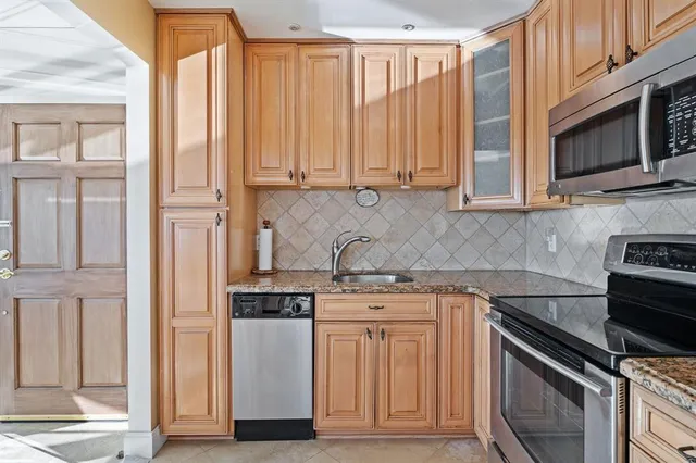 a kitchen with stainless steel appliances granite countertop a stove a sink and a microwave