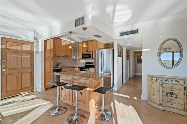 a kitchen with stainless steel appliances kitchen island granite countertop a refrigerator and microwave