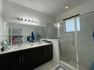 a bathroom with a double vanity sink mirror and shower