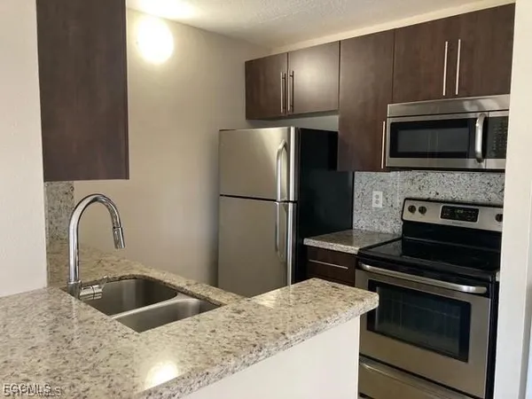 a kitchen with granite countertop a refrigerator stove and microwave