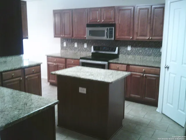 a kitchen with granite countertop a refrigerator and a sink