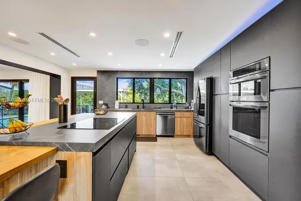 a kitchen with stainless steel appliances kitchen island a table and chairs in it