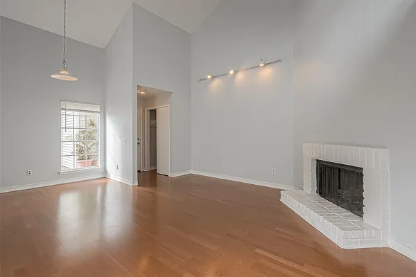 an empty room with wooden floor fireplace and windows