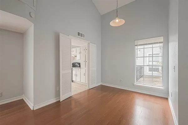an empty room with wooden floor and windows