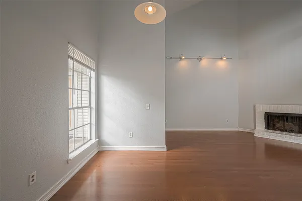an empty room with windows and fireplace