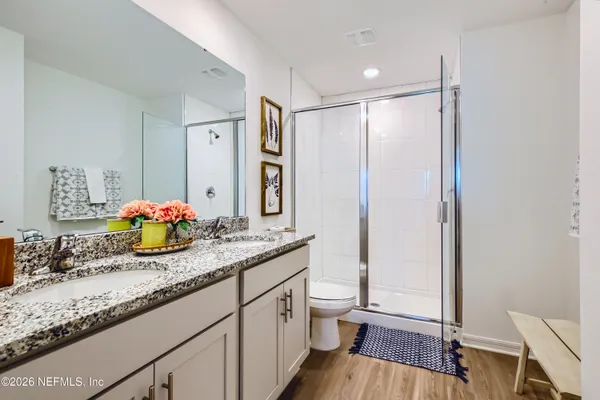 a bathroom with a granite countertop sink a toilet a mirror and shower