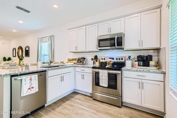 a kitchen with stainless steel appliances granite countertop a stove and white cabinets