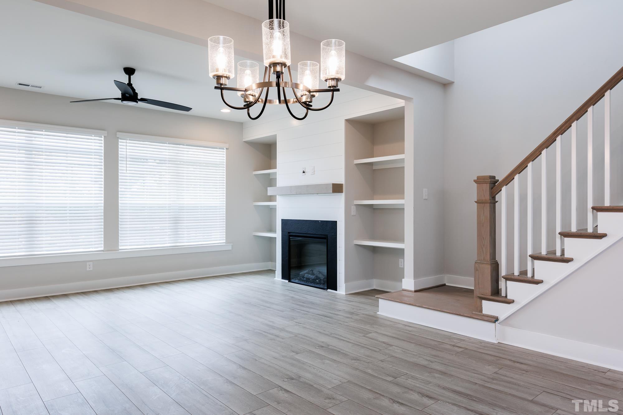 a view of an empty room with wooden floor fireplace and a window