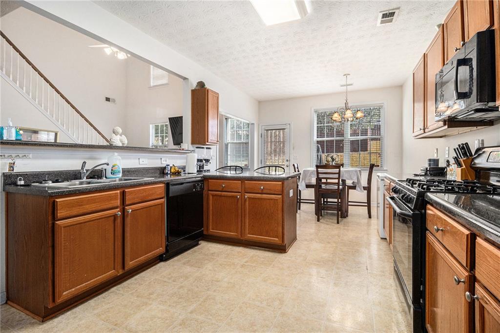 5610 Swanson Road Ellenwood, GA 30294 - Photo 10 of 28 a kitchen with stainless steel appliances granite countertop a stove top oven a sink a dining table and chairs