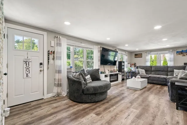 a living room with stainless steel appliances kitchen island granite countertop furniture a rug a fireplace and a window