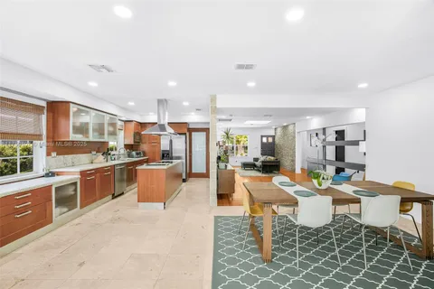 a kitchen with stainless steel appliances granite countertop a stove top oven a sink dishwasher a dining table and chairs with wooden floor