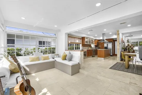 a living room with furniture a flat screen tv and kitchen view