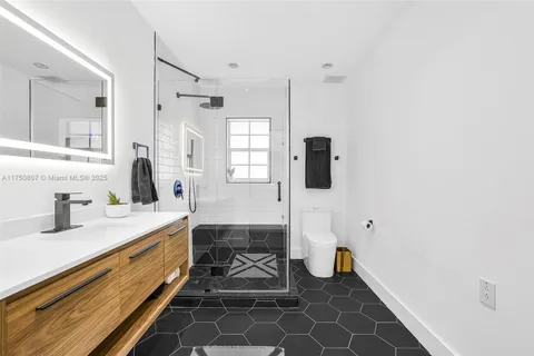 a bathroom with a granite countertop sink a mirror and shower