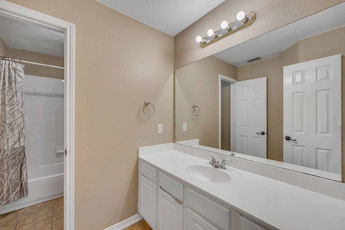 2726 Grimes Ranch Road Austin, TX 78732 - Photo 10 of 35 Bathroom featuring shower / tub combo, vanity, a textured wall, and light tile patterned floors