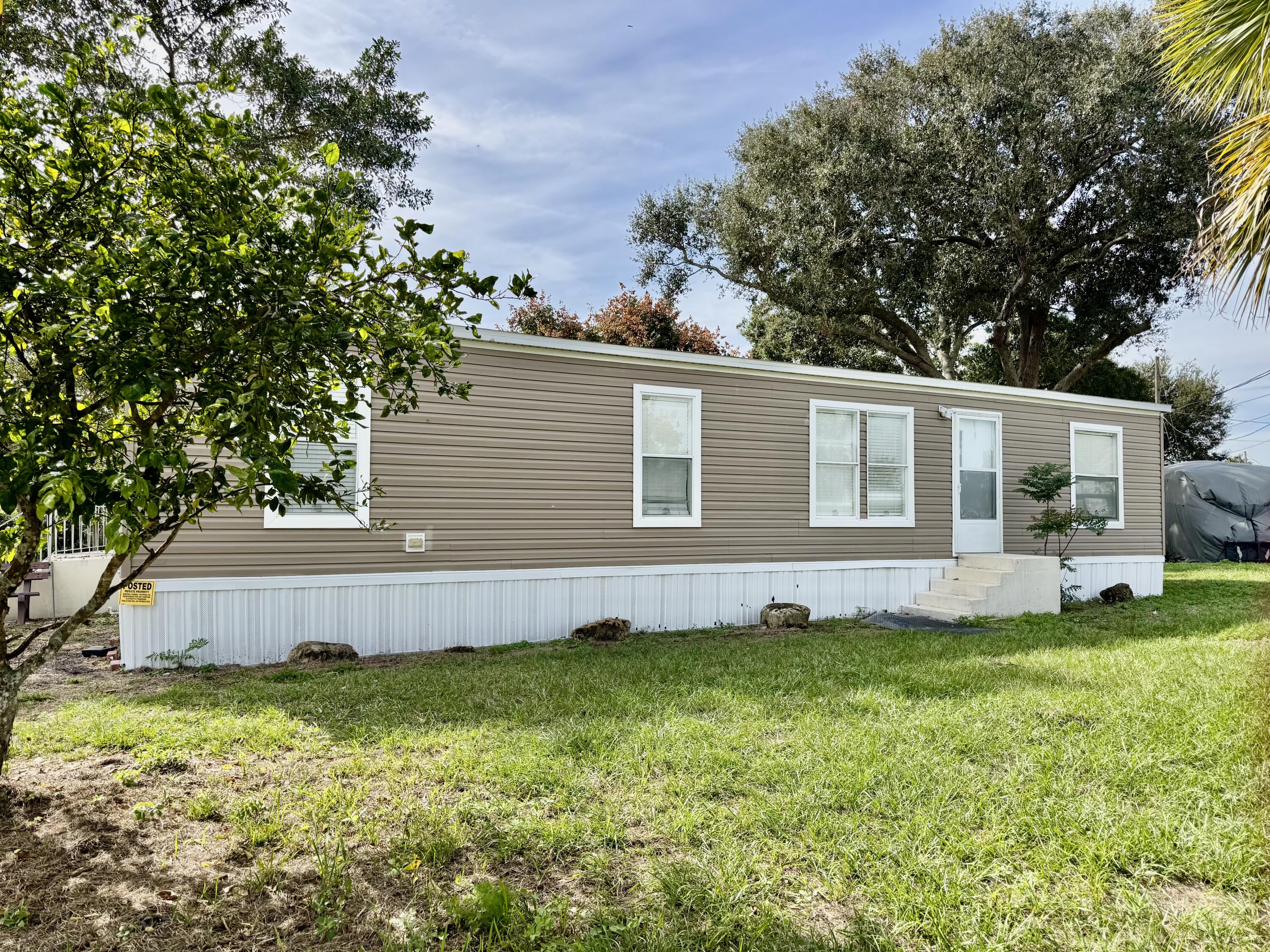 3200 Southeast 18th Court Okeechobee, FL 34974 - Photo 19 of 21 a view of a house with a big yard potted plants and large tree