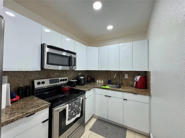 a kitchen with stainless steel appliances granite countertop a sink stove and microwave