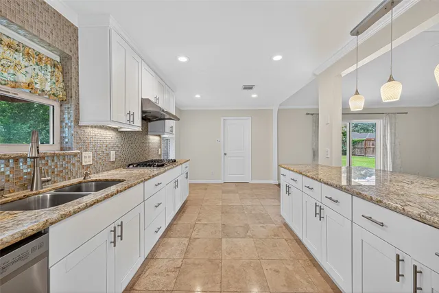 a large kitchen with granite countertop a sink and white cabinets