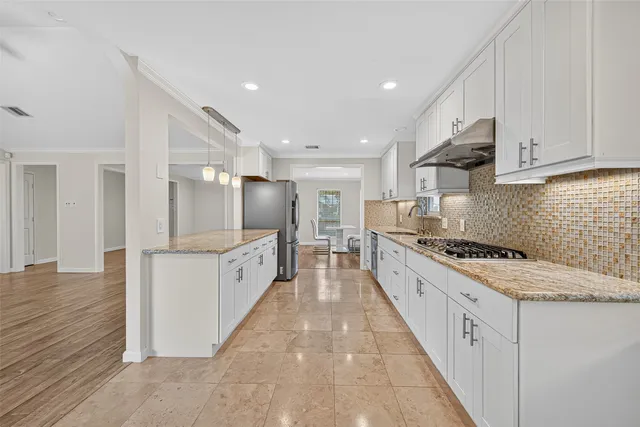 a large kitchen with white cabinets stainless steel appliances