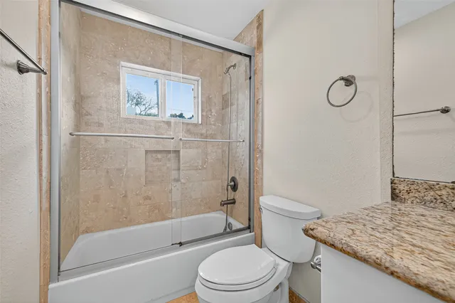 a bathroom with a granite countertop toilet a sink and bathtub